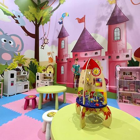 Evergreen Laurel Hotel - Taichung Exterior foto The photo shows a colorful children's playroom designed with a whimsical theme. The walls are painted in bright colors and feature a cartoon-style mural of a pink castle with purple towers and a smiling cartoon elephant. The room is filled with playf
