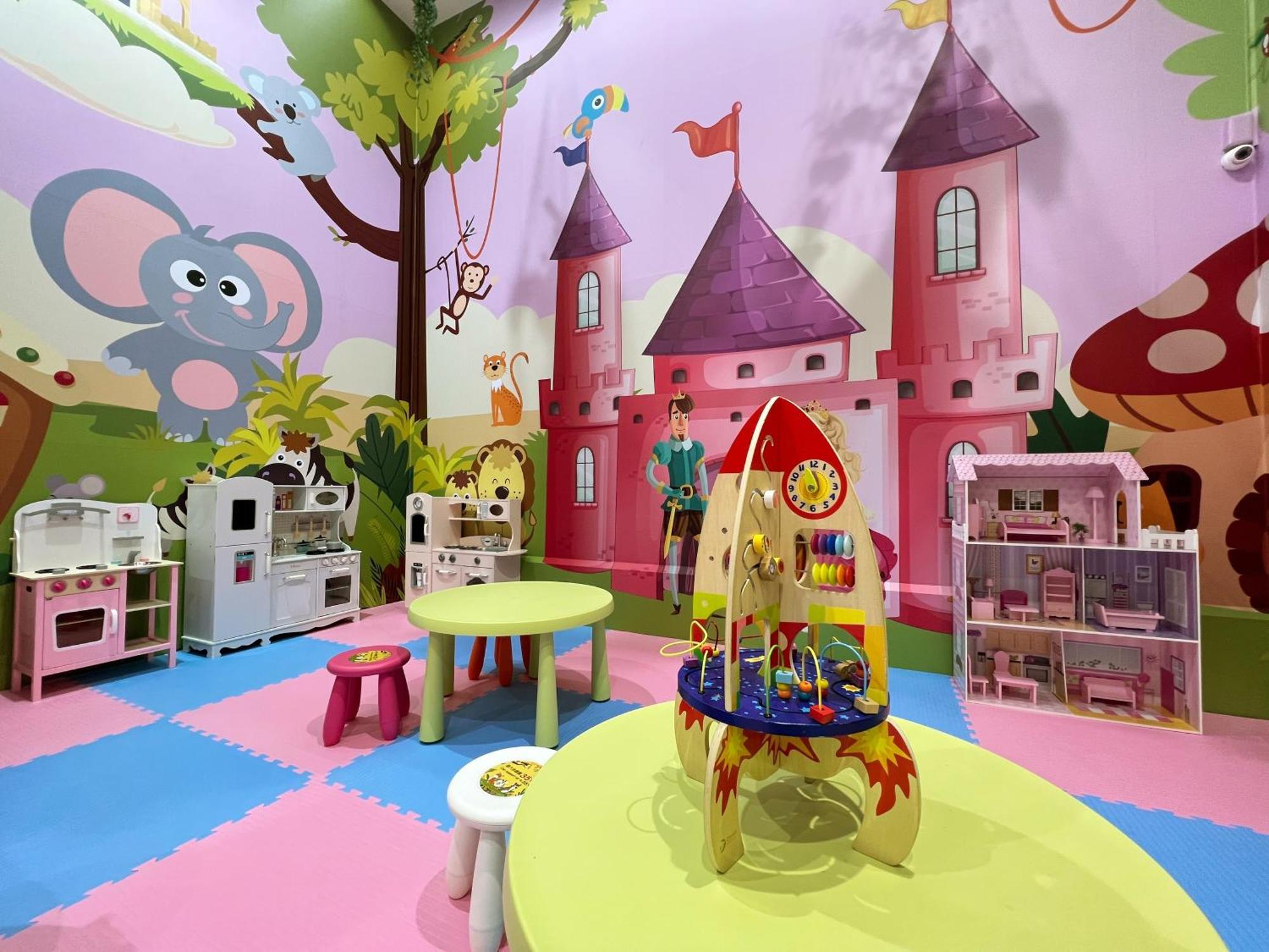 Evergreen Laurel Hotel - Taichung Exterior foto The photo shows a colorful children's playroom designed with a whimsical theme. The walls are painted in bright colors and feature a cartoon-style mural of a pink castle with purple towers and a smiling cartoon elephant. The room is filled with playf