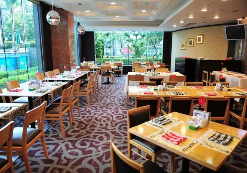 Evergreen Laurel Hotel - Taichung Exterior foto The photo shows an interior of a restaurant with a spacious layout. There are several wooden tables, each set with napkins and utensils. The floor has a decorative carpet, and large windows provide a view of greenery outside. The lighting is bright, 
