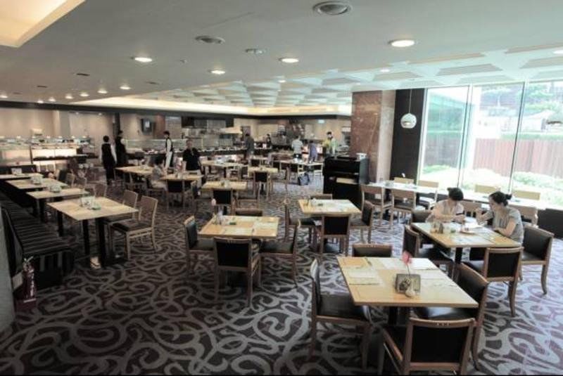 Evergreen Laurel Hotel - Taichung Exterior foto The photo shows a spacious restaurant or dining area with a modern interior design. There are several tables arranged throughout the room, some of which are set for dining while others appear to be empty. The decor includes a patterned carpet and lar