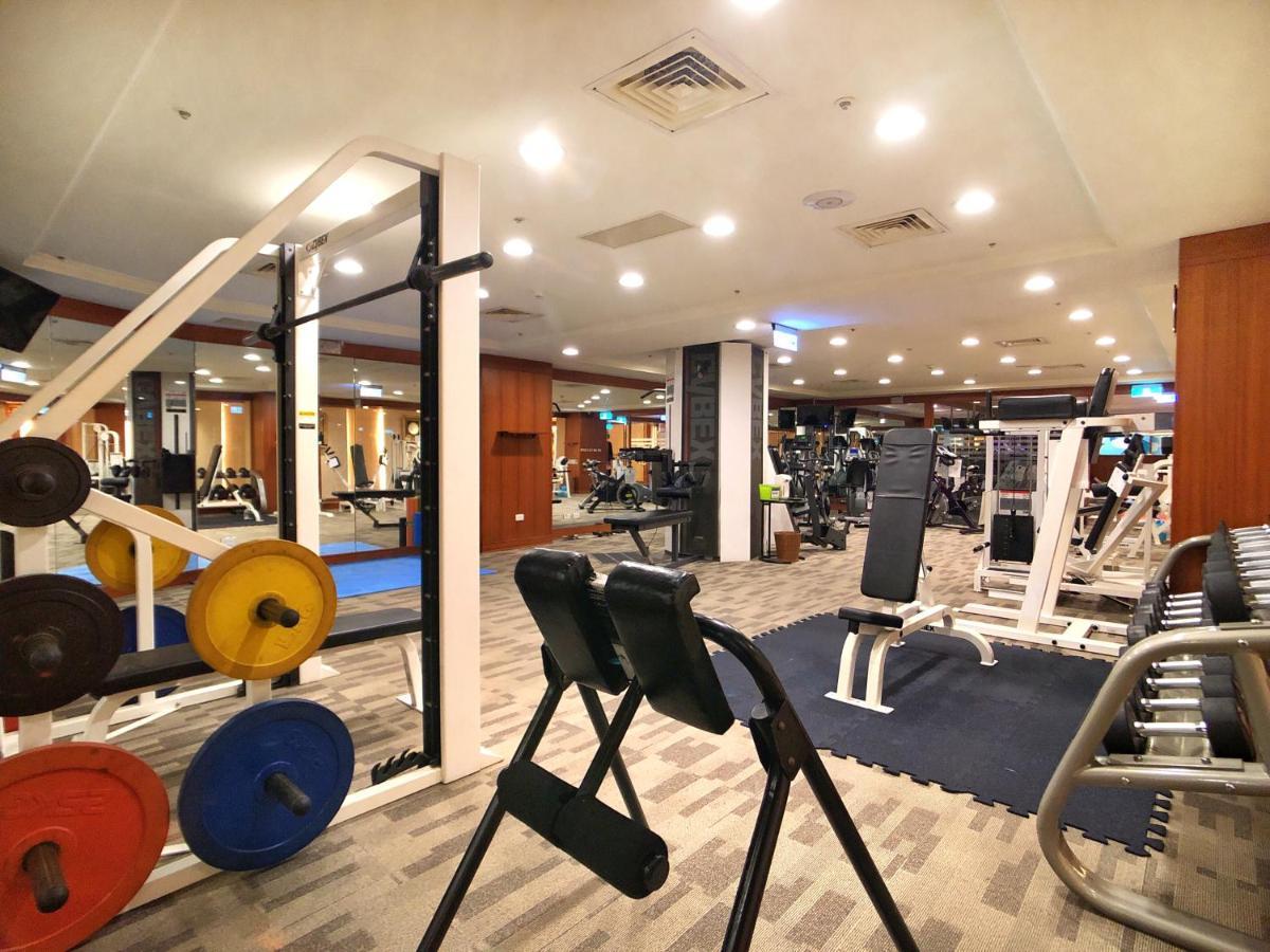 Evergreen Laurel Hotel - Taichung Exterior foto The photo shows a gym interior with various workout equipment. On the left, there are weights of different colors stacked on a weight rack. In the foreground, there's a bench for exercises, and in the background, multiple machines for strength traini